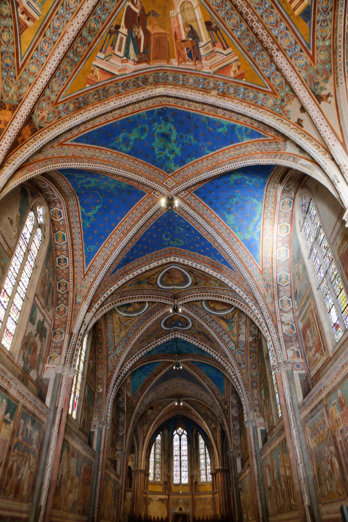 La navata della Basilica Superiore di Assisi vista dal basso, con le volte a crociera stellate e i cicli di affreschi sulle pareti.