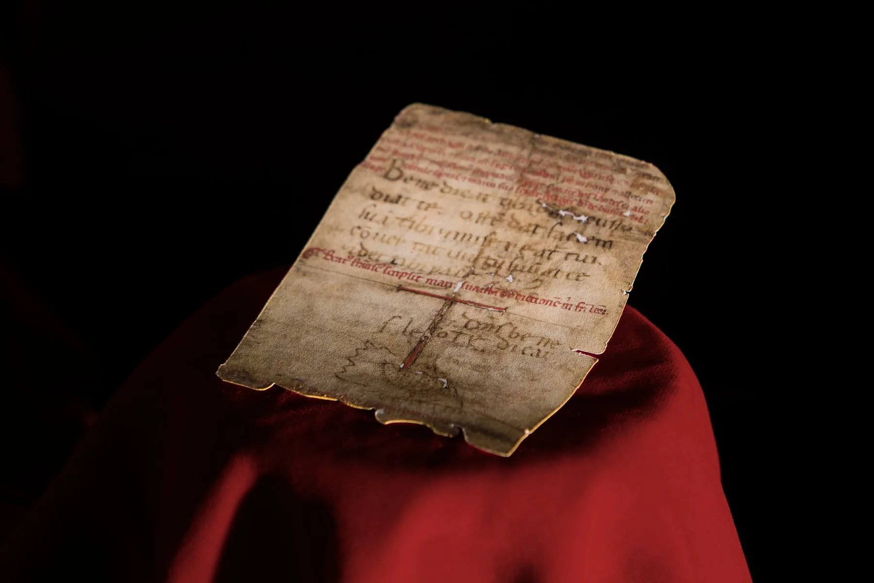 The Chartula of Assisi, in the hand of Saint Francis: the parchment bearing the Laudes Dei Altissimi and the Blessing to Brother Leo, laid on red cloth.