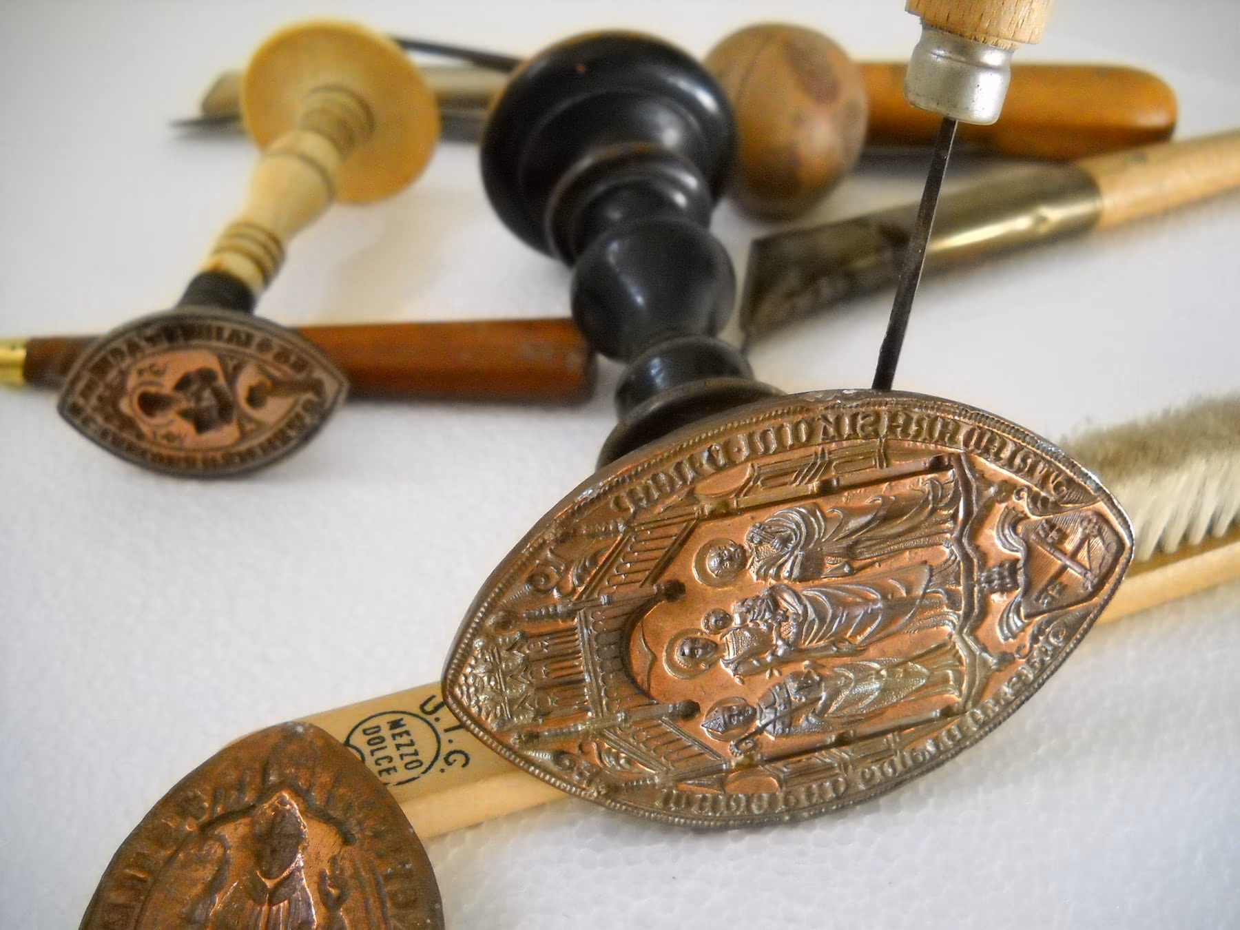 Metal seal matrices and sealing wax tools resting on a surface.