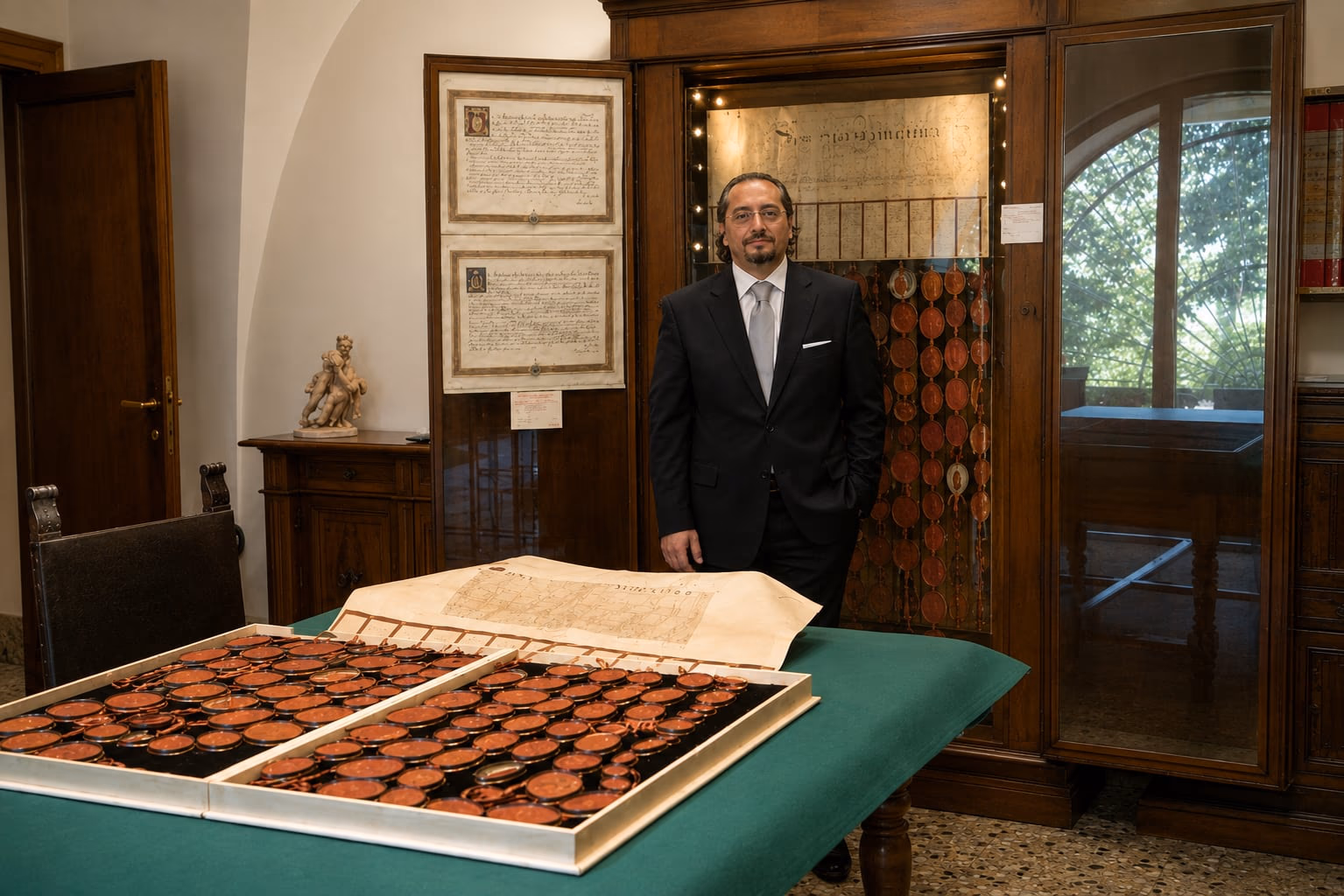 The president of Scrinium beside an open document with pendant seals, in the archive room.