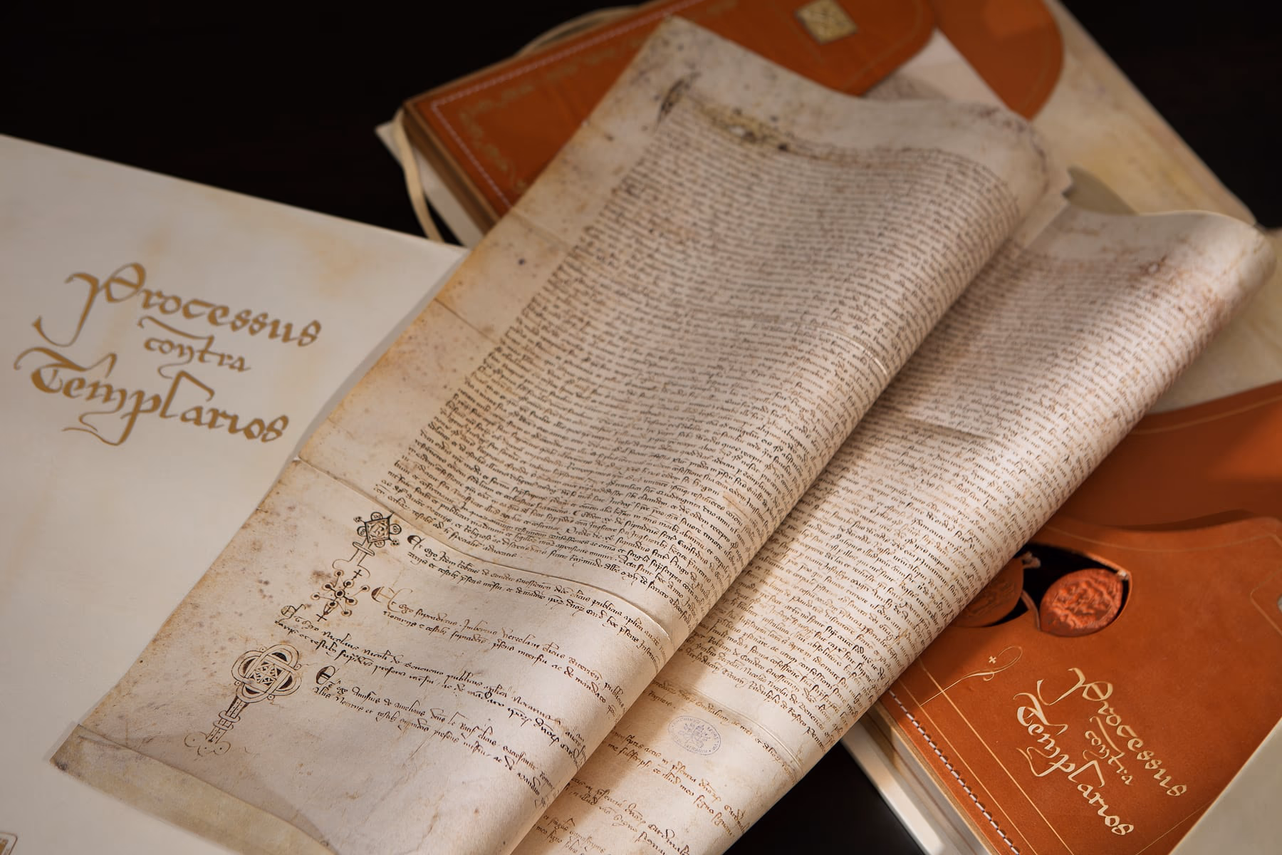 The parchment of the Processus contra Templarios, rolled beside the facsimile volume.