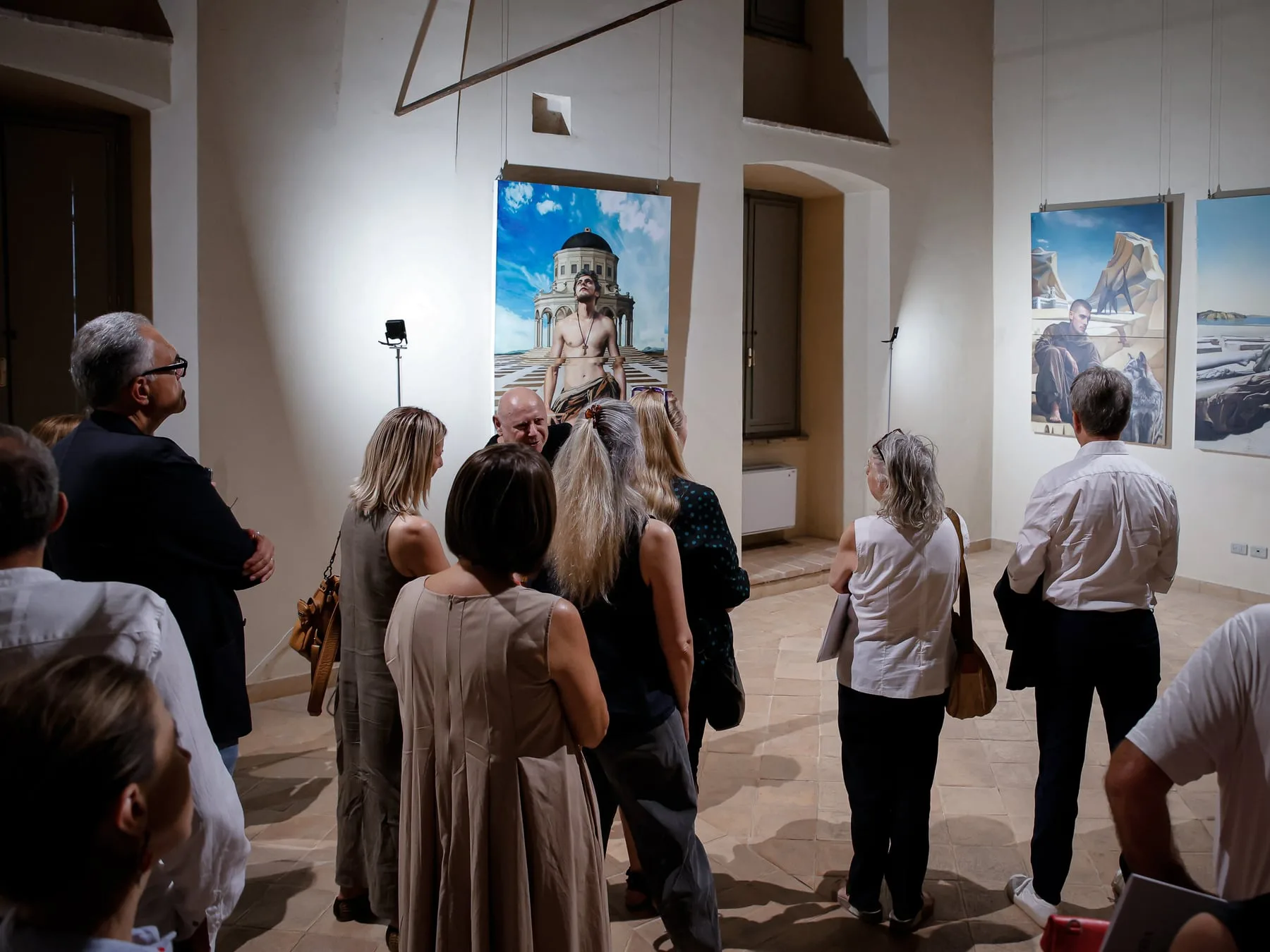 Un gruppo di visitatori di spalle in una sala affrescata di Palazzo Trinci, davanti alle opere appese ai pannelli.